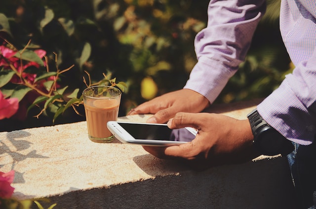 Man outdoors playing online casino on his phone while drinking a beverage